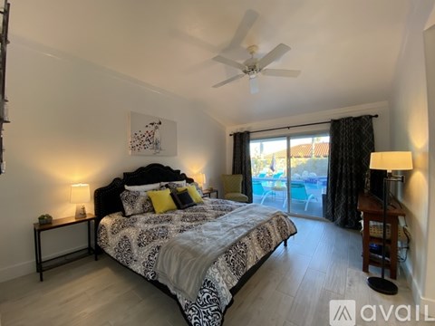 A bedroom with a large bed and a balcony overlooking a pool.