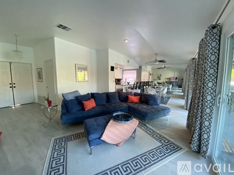 A living room with a blue couch and a pink ottoman.