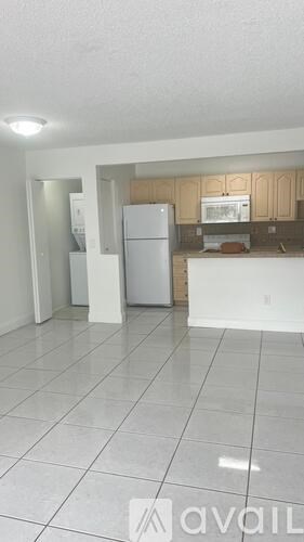 A kitchen with a white fridge and white tiled floor.