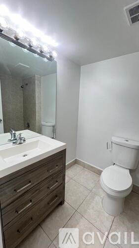 A bathroom with a toilet, sink, and mirror.