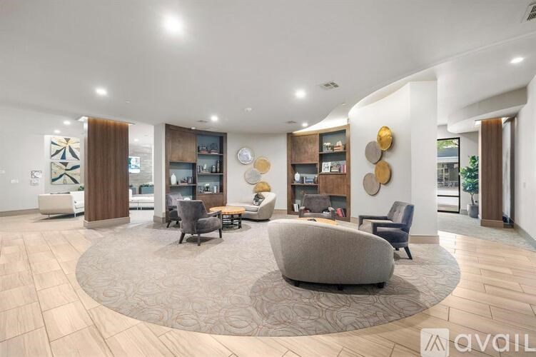 A spacious living room with a large circular rug in the center and a variety of seating options.