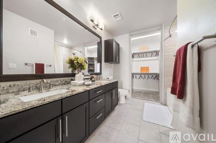 A bathroom with a sink, mirror, and a red towel hanging on the door.