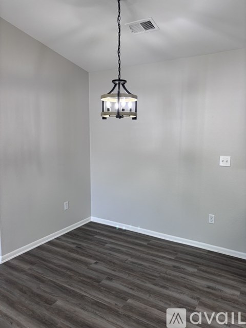 A room with a wooden floor and a hanging light fixture.