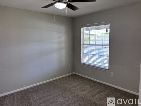 A room with a ceiling fan and a window with blinds.