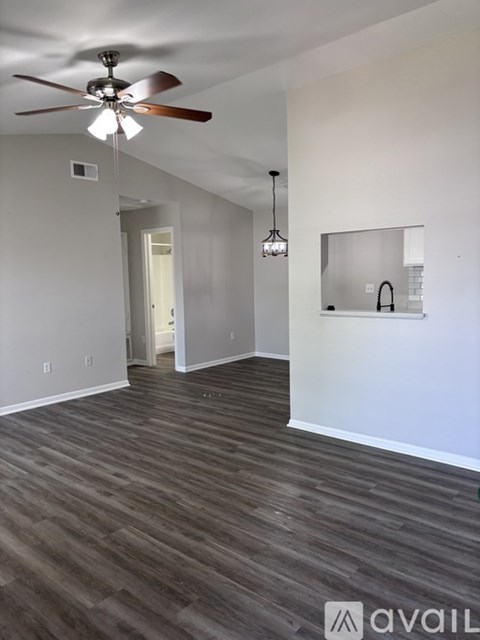 A room with a ceiling fan and wooden flooring.