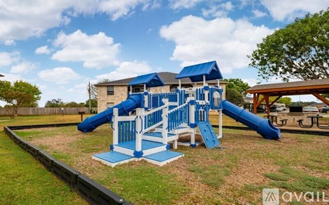 A playground with a blue slide and white railings.
