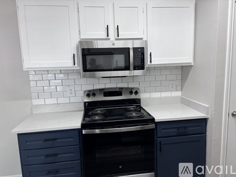 A kitchen with white cabinets and a black stove top oven.