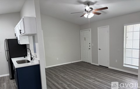 A kitchen area with a sink, a refrigerator, and a ceiling fan.