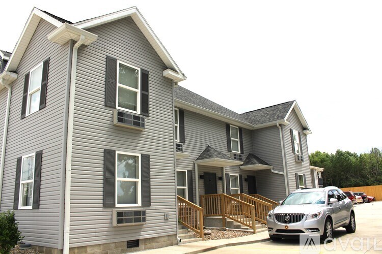 A grey house with a car parked in front.