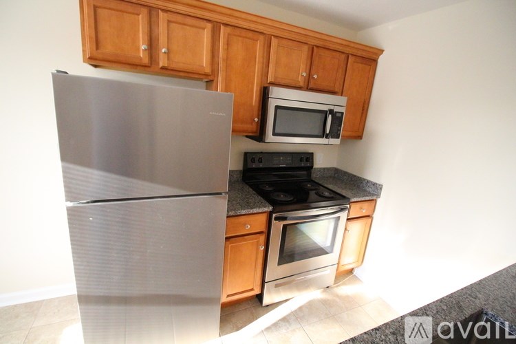 A kitchen with wooden cabinets and a stainless steel refrigerator.