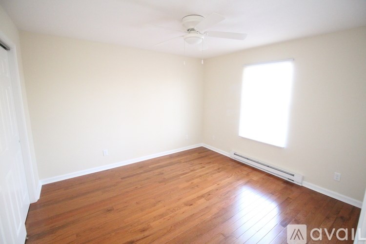 A room with wooden floors and a window letting in sunlight.