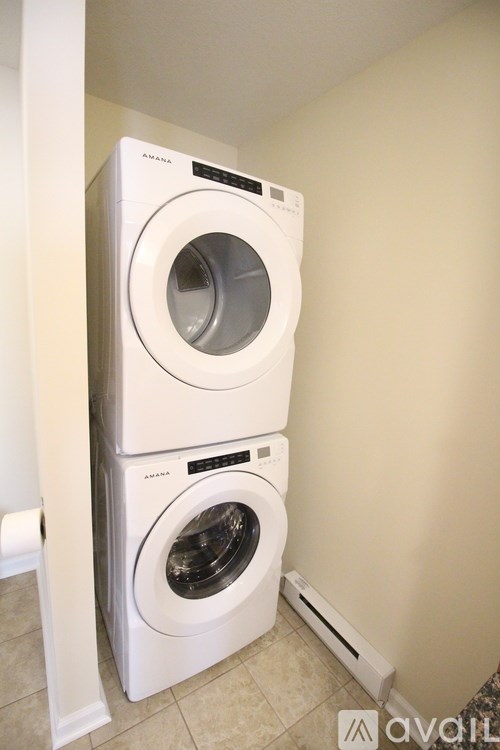 Two white front loading washing machines in a small laundry room.