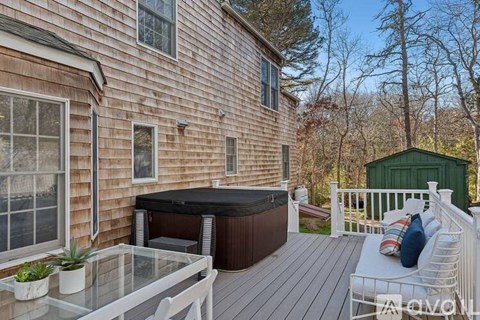 A wooden deck with a hot tub and a glass table.