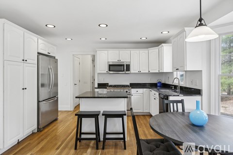 A kitchen with white cabinets and a black table.