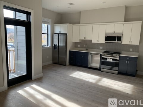 A kitchen with white cabinets and a black refrigerator.