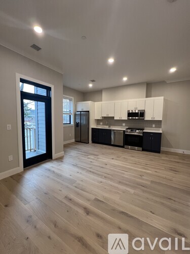 A spacious kitchen with wooden flooring and white cabinets.