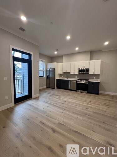 A spacious kitchen with wooden flooring and white cabinets.