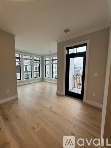 A spacious room with wooden floors and a large window.
