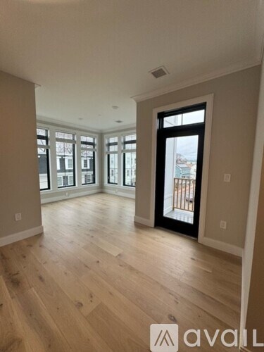A spacious room with wooden floors and a large window.