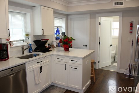 A kitchen with white cabinets and a wooden stool.