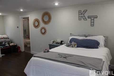A bedroom with a large bed and a wall decoration that spells "KT".