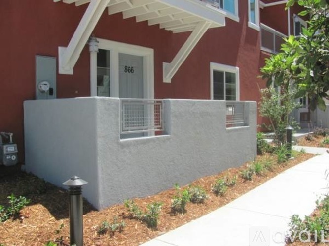 A red house with white trim and a grey concrete wall.