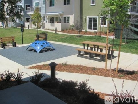 A playground with a blue shade structure and a picnic table.