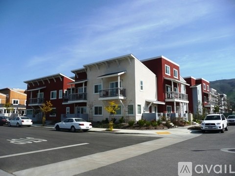 A row of modern apartment buildings with cars parked in front.