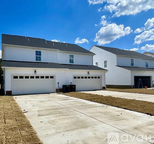A white two-story house with a garage door and a driveway.