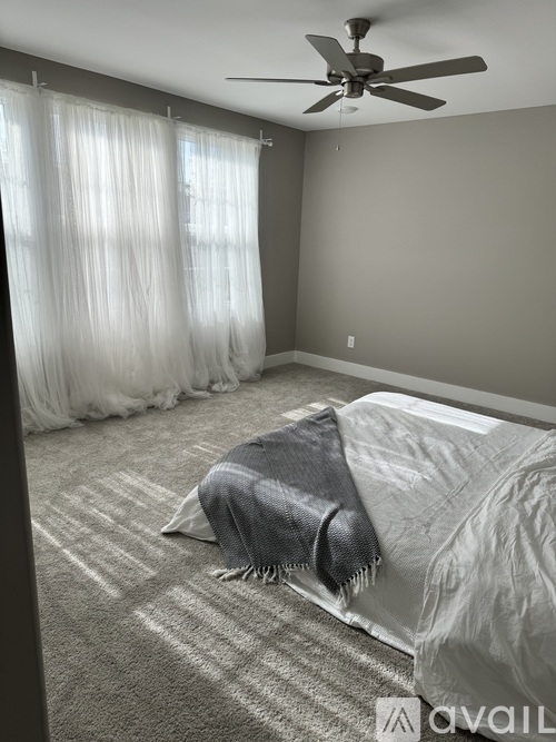 A bedroom with a bed covered in a blanket and a ceiling fan.