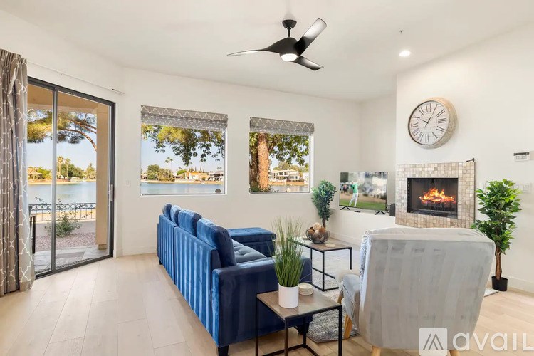 A living room with a blue sofa, a grey armchair, a fireplace, and a ceiling fan.
