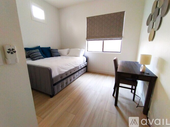 A bedroom with a bed, table, and window.