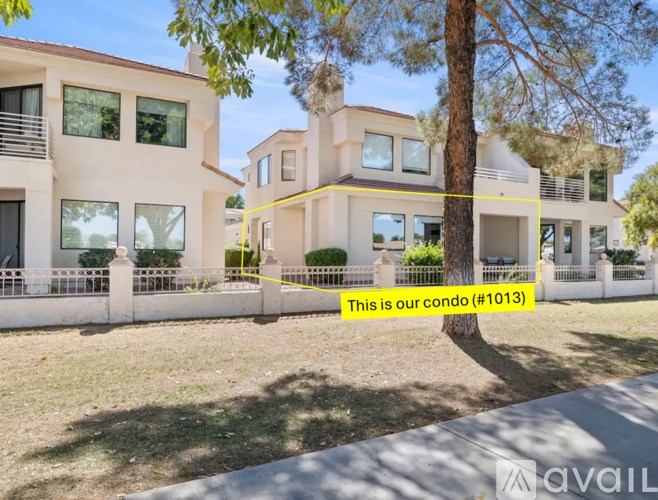 A modern house with a white fence and a tree in front.