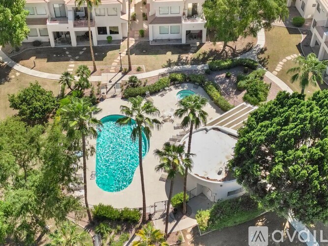 A pool surrounded by trees and a building in the background.