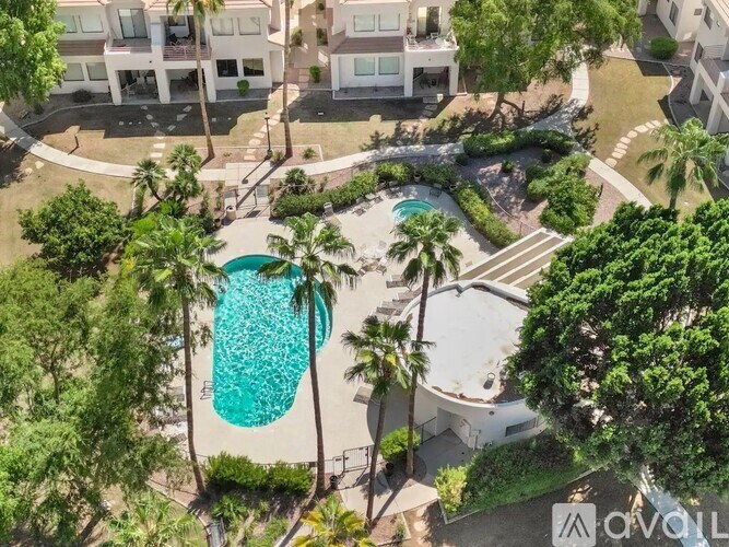 A pool surrounded by trees and a building in the background.