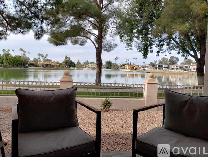 Two chairs are placed on a patio overlooking a lake.
