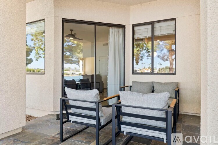 Two chairs are placed on a patio with a table and a fan.