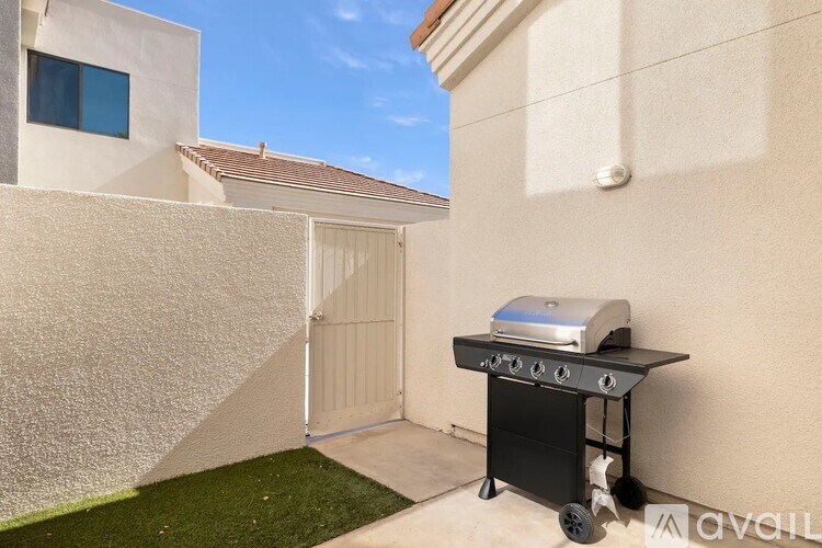 A barbecue grill is placed on a patio in front of a house.