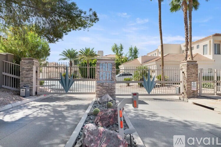 A gated community entrance with a sign that reads "AVAIL" and palm trees in the background.