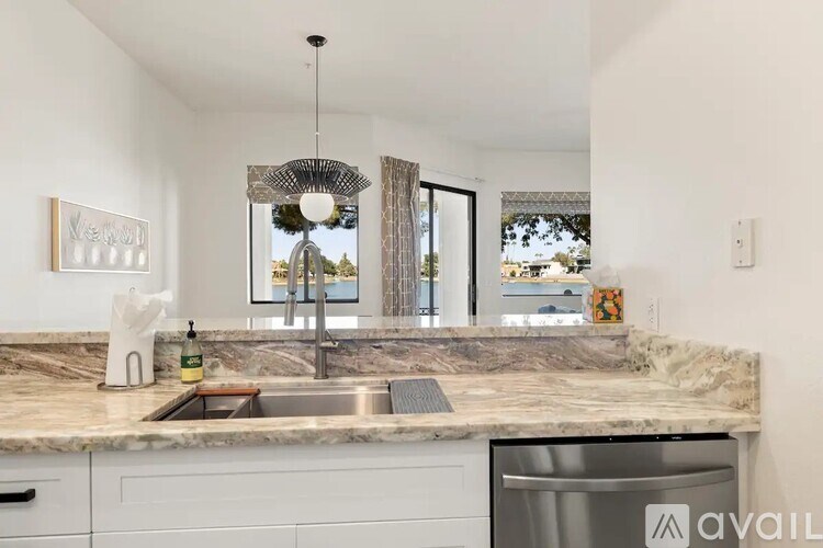 A kitchen with a marble countertop and a stainless steel dishwasher.