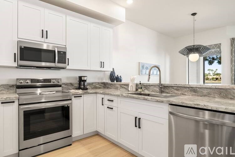 A modern kitchen with white cabinets and stainless steel appliances.