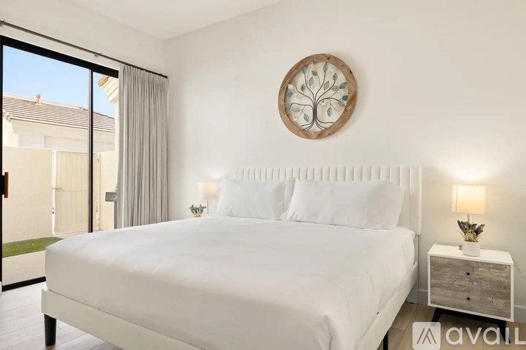 A bedroom with a large bed, a round decorative piece on the wall, and a window with a view of the outside.