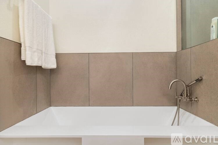 A white bathtub with a silver faucet and a white towel hanging on the wall.