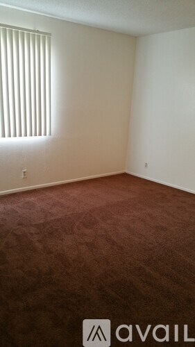 A room with a wooden floor and a window with blinds.
