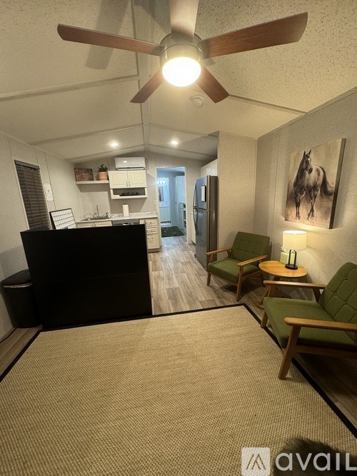 A living room with a black couch and a ceiling fan.