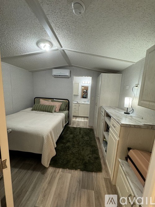 A small bedroom with a bed, a desk, and a chair.