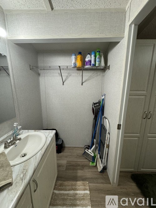 A bathroom with a sink, mirror, and a few items on the floor.