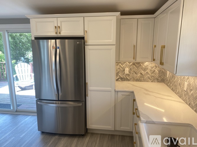 A modern kitchen with a stainless steel refrigerator and white cabinets.