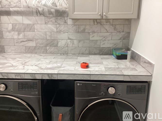A red tape measure is on a marble countertop above a washing machine.