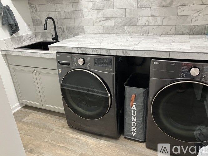 Two black front loading washing machines in a laundry room.